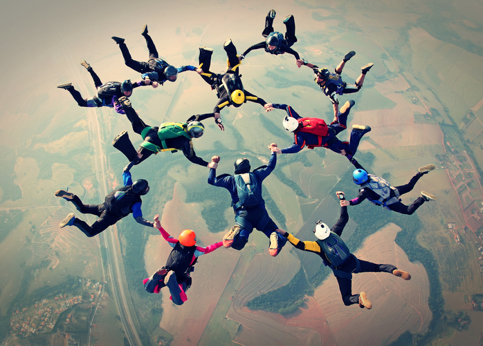 Skydiving teammates in formation holding hands
